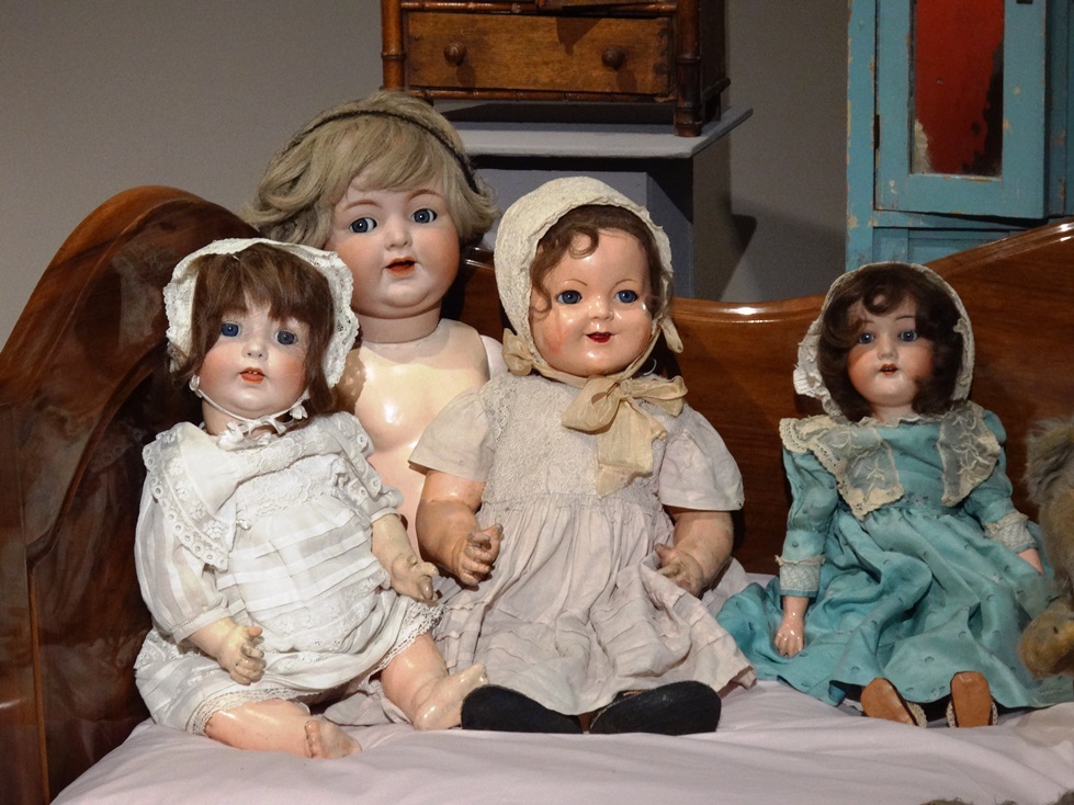 Four dolls in bright dresses, seated on the bed. The dolls come from Marek Sosenko collection. Photo by Dorota Zoladz-Strzelczyk.